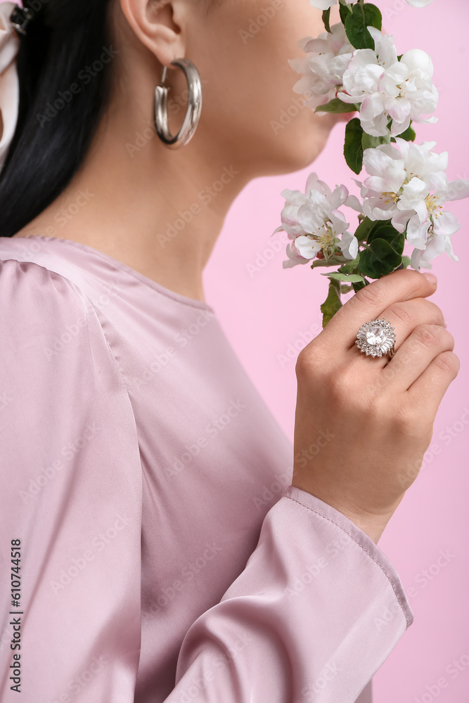 Profile of beautiful young woman wearing stylish jewelry with flower near pink wall