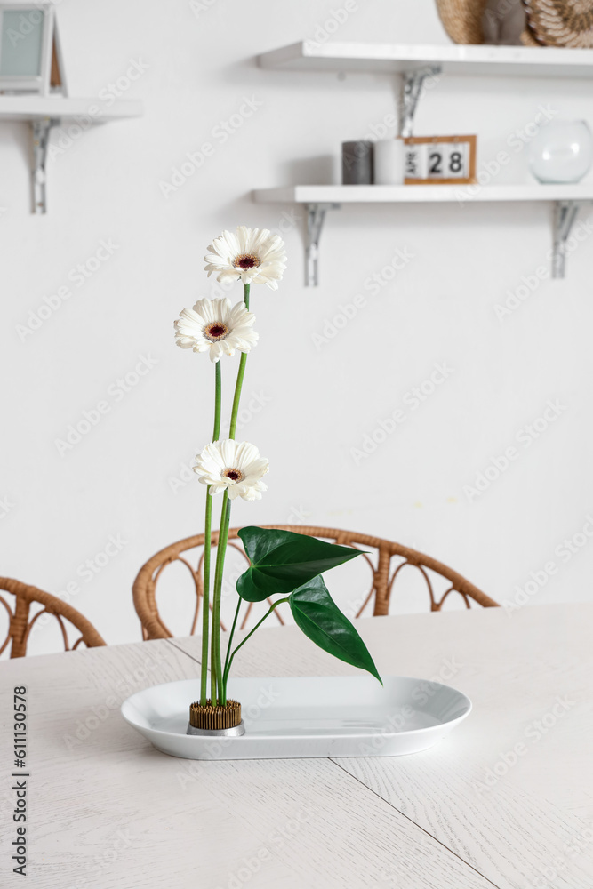 Beautiful ikebana on dining table in room