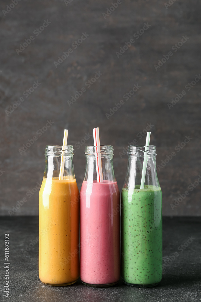 Bottles of colorful smoothie on dark table