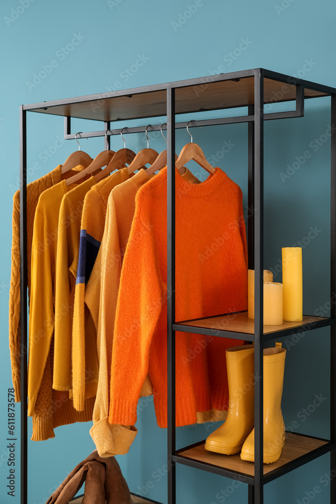 Shelving unit with clothes, candles and shoes near blue wall