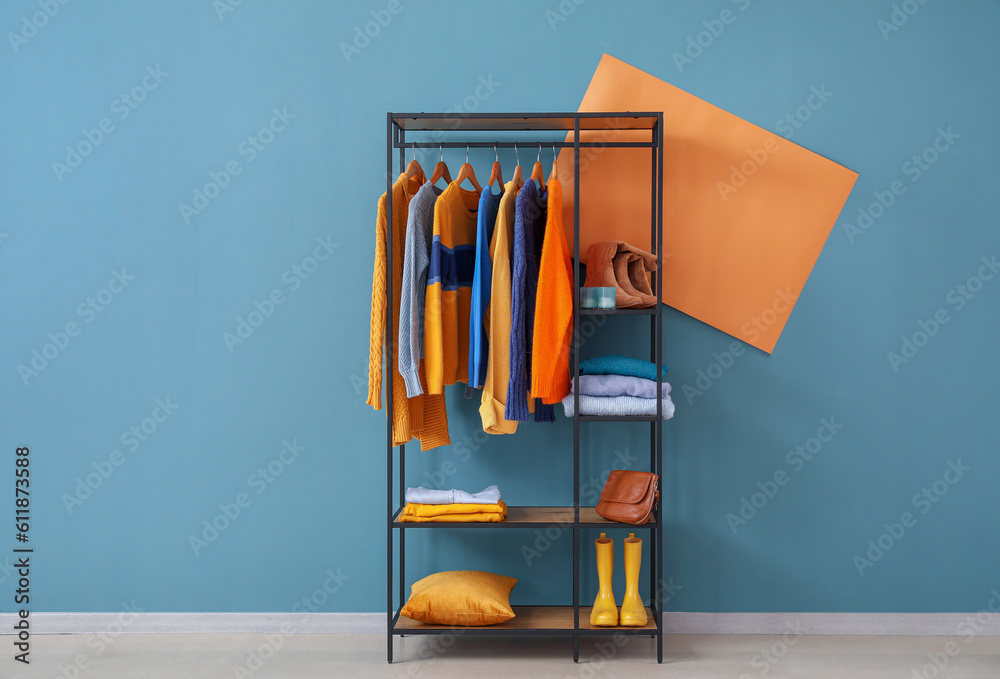 Shelving unit with clothes and shoes near blue wall