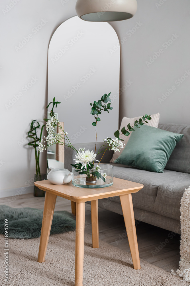 Interior of living room with ikebana on table and sofa