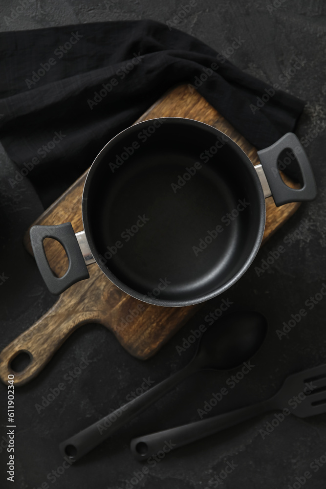 Cooking pot and kitchen utensils on dark background