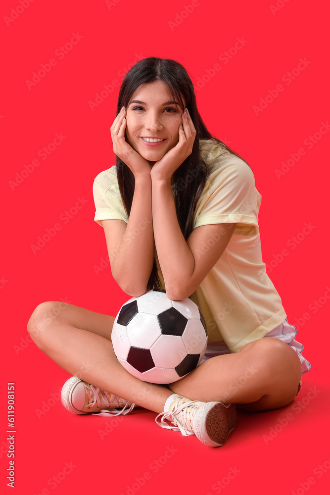 Young woman with soccer ball on red background
