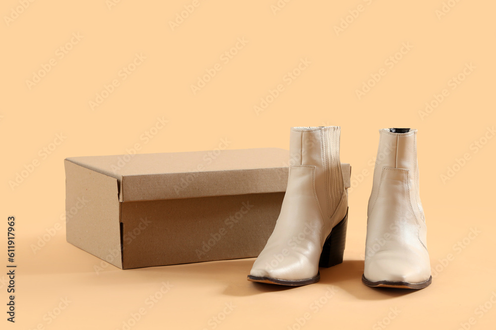 Cardboard box with heeled shoes on beige background