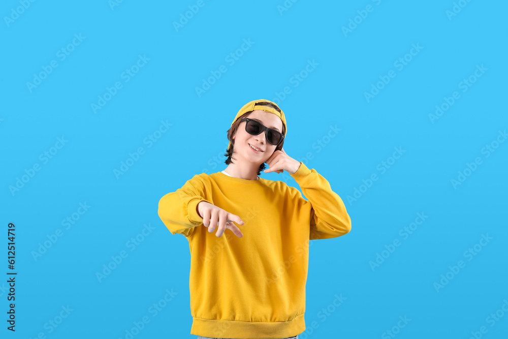 Cool teenage boy showing  call me  gesture on blue background