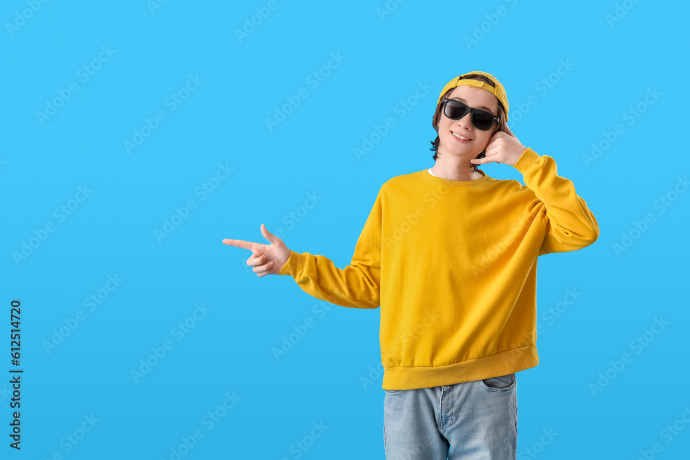 Cool teenage boy showing  call me  gesture on blue background