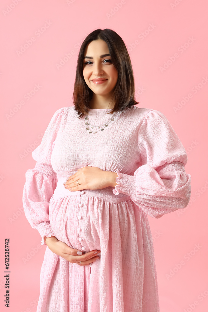 Young pregnant woman in beautiful dress on pink background