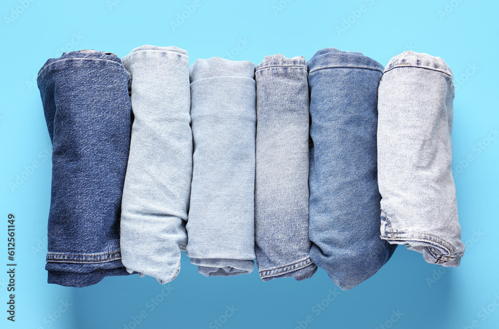 Different folded jeans on blue background