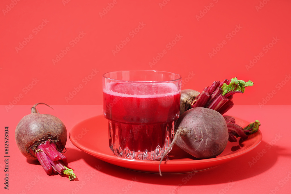 Plate with glass of healthy beet juice on red background