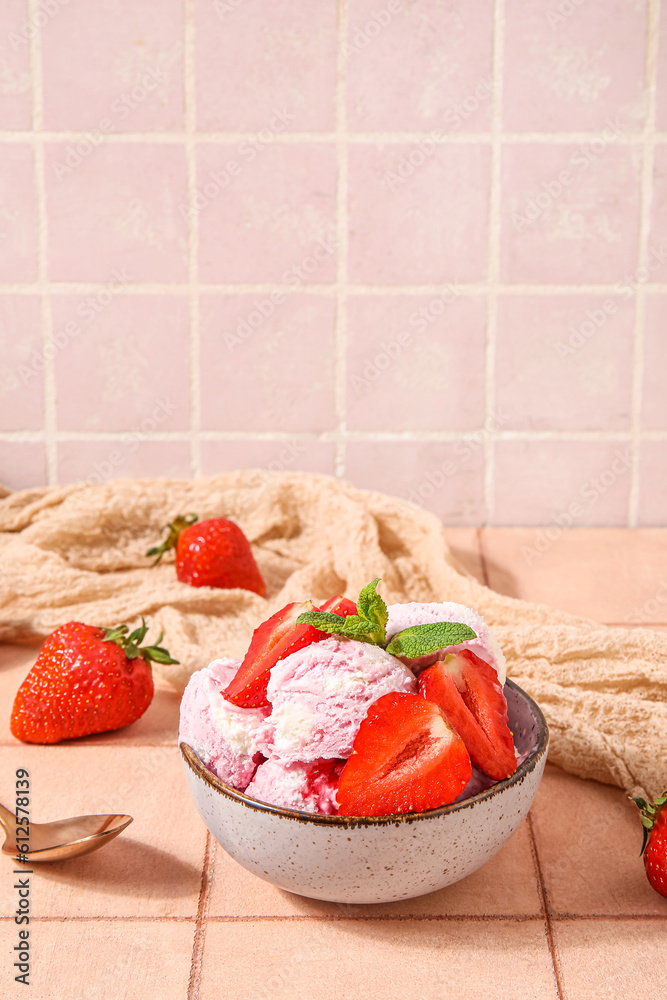 Bowl of strawberry ice cream with berries, mint and spoon on beige tile table near pink wall