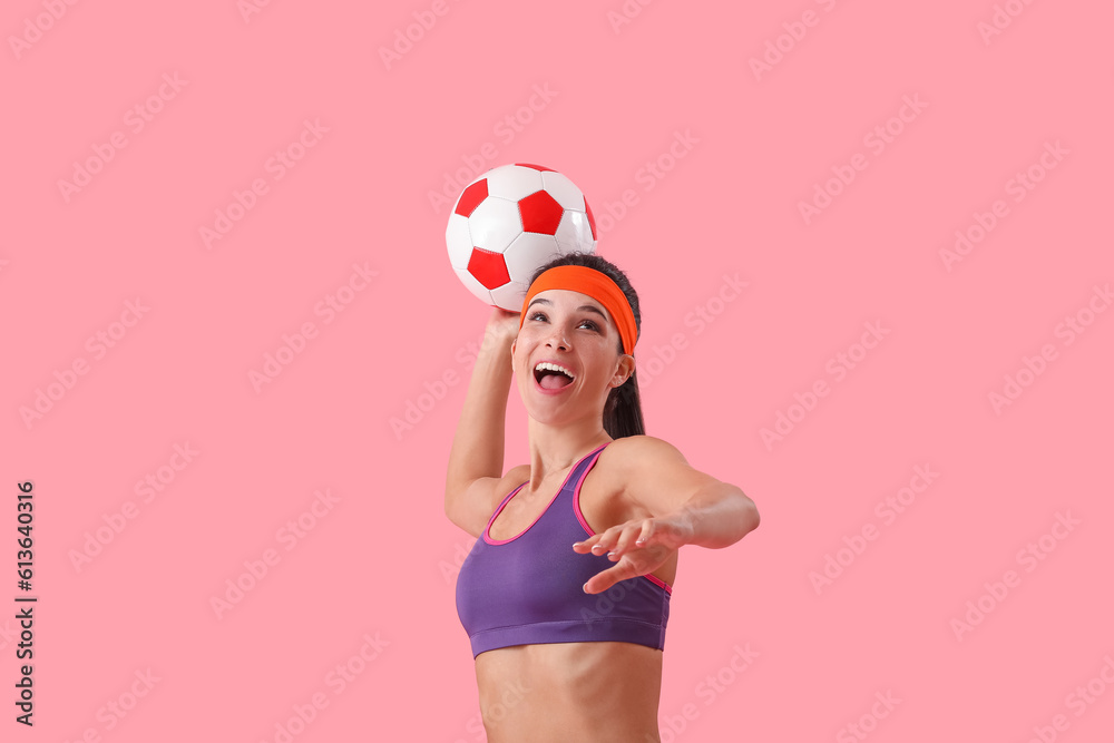 Sporty young woman with soccer ball on pink background