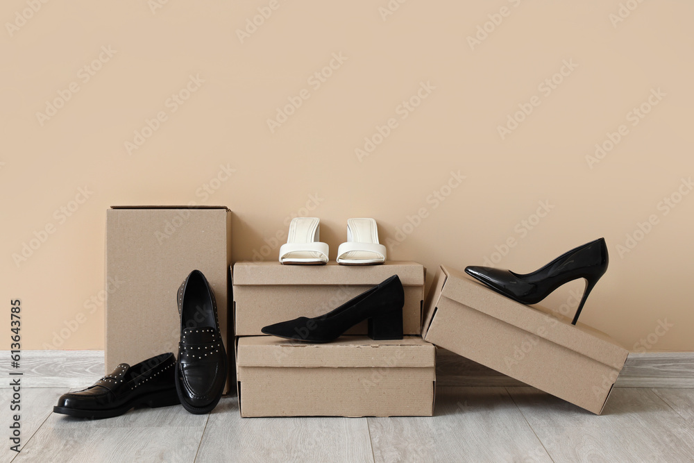 Cardboard boxes with different high-heeled shoes near color wall
