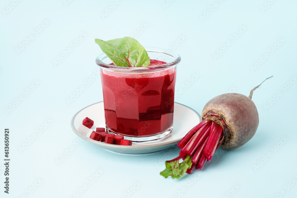 Plate with glass of healthy beet juice and spinach on blue background