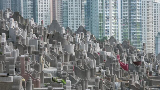 View of hundreds of tombstones at a crowded cemetery as residential buildings are seen in the background.