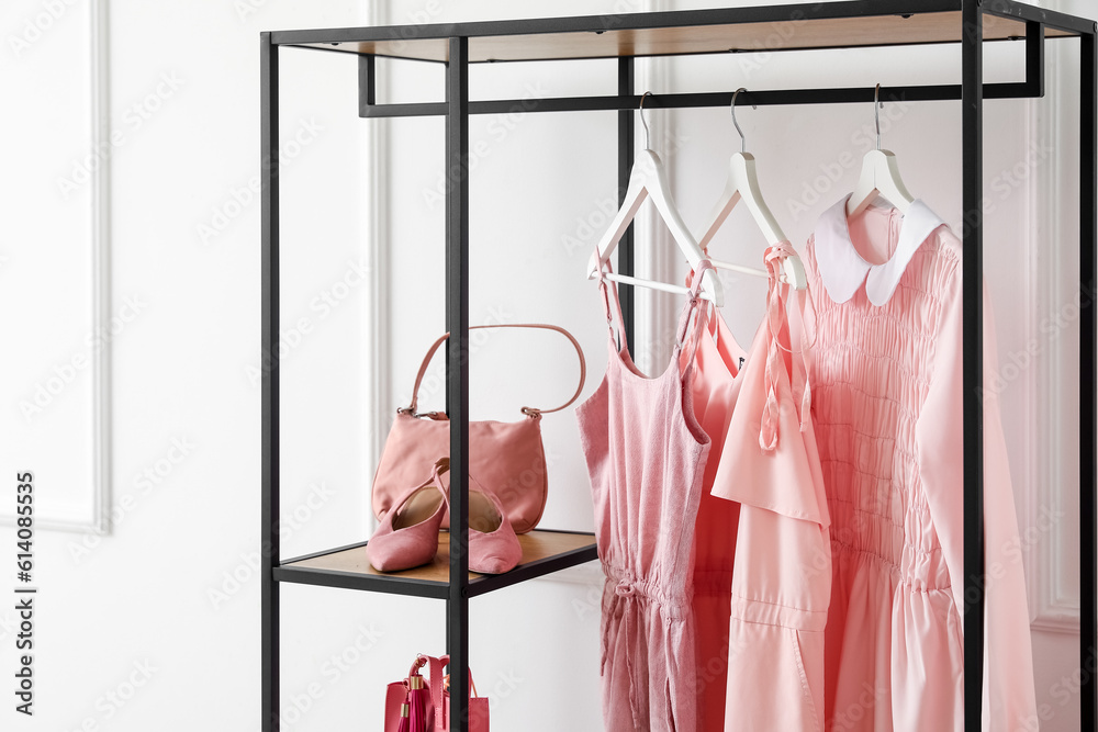 Shelving unit with clothes, bag and shoes near light wall