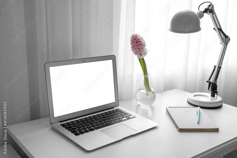 Comfortable workplace with modern laptop and beautiful hyacinth flowers near window
