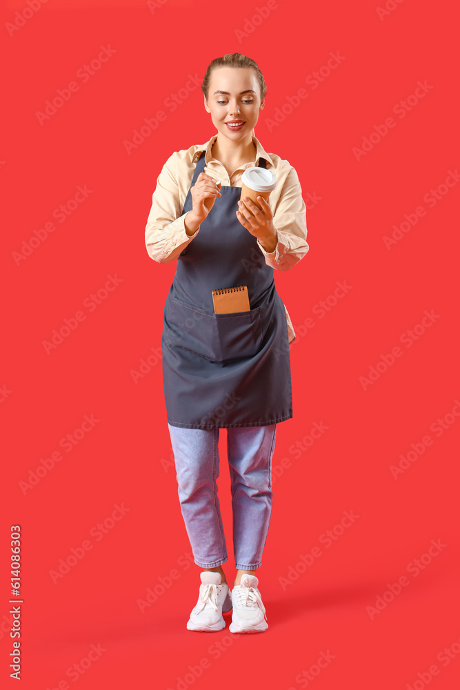 Young barista with cup of coffee on red background