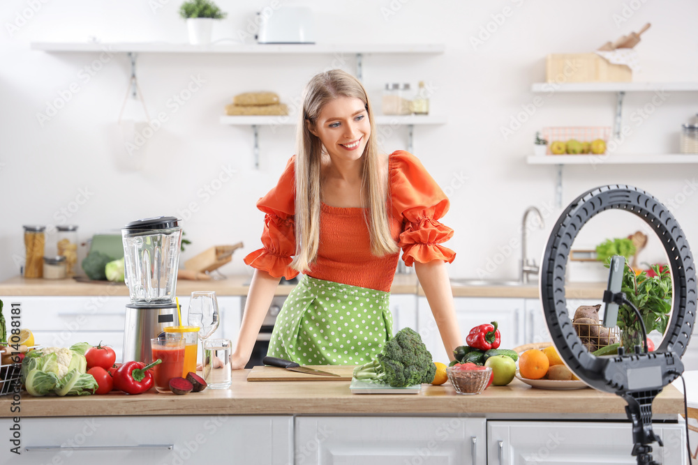 Female blogger with fresh vegetables recording cooking video in kitchen