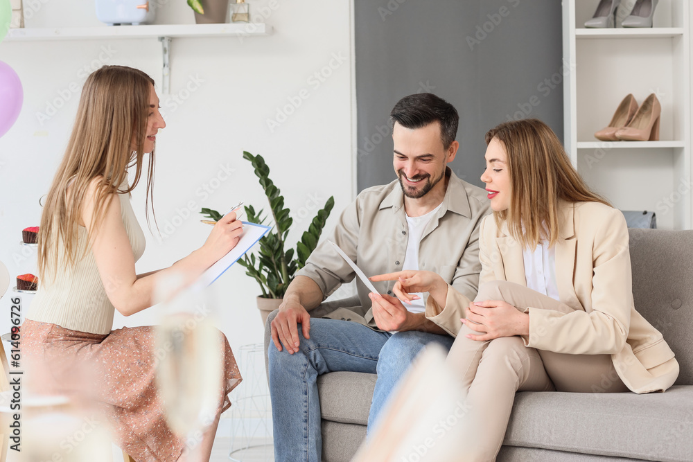Young couple with wedding planner choosing color palette in office