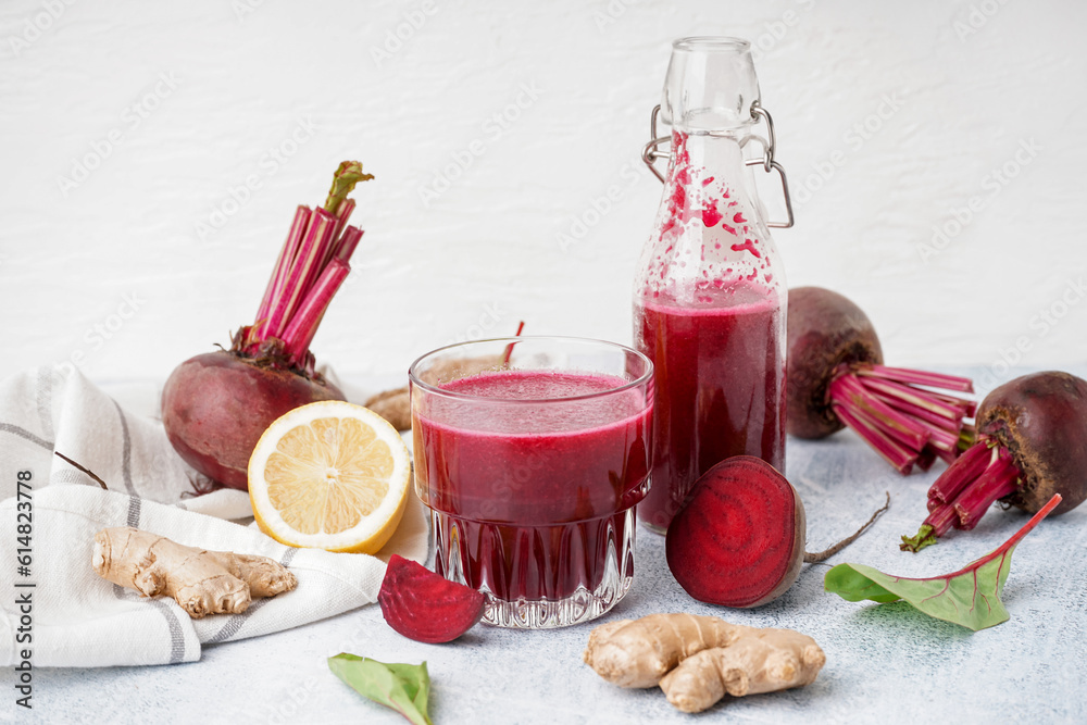 Bottle and glass of fresh beetroot juice with ingredients on light background