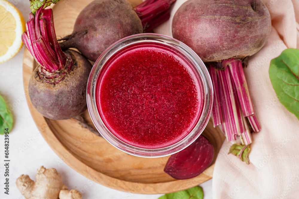 Glass of fresh beetroot juice and vegetables on light background