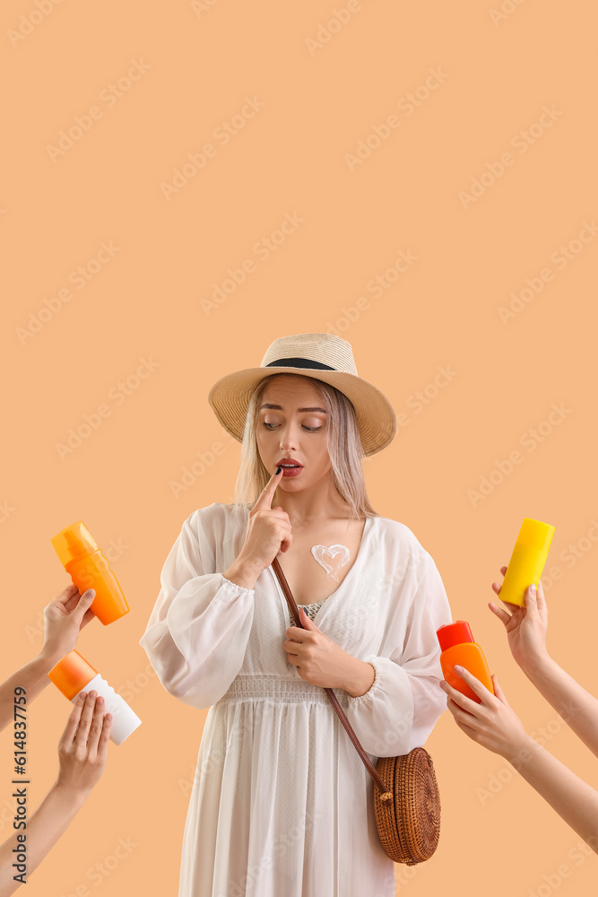 Thoughtful young woman and female hands with bottles of sunscreen cream on beige background