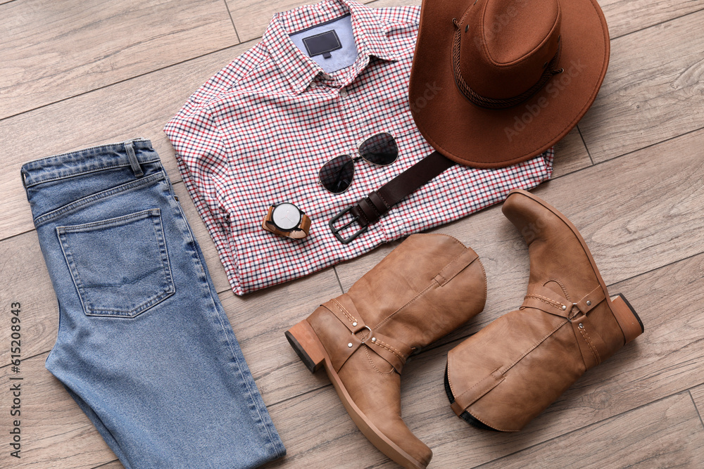 Male clothes with cowboy boots and accessories on wooden floor