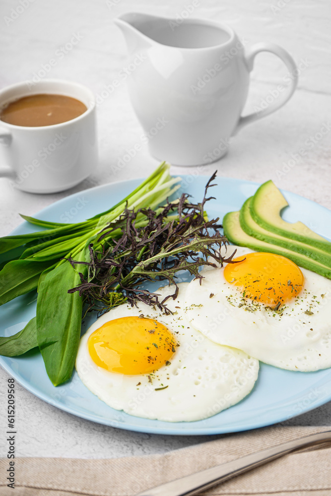 Plate with tasty fried eggs, coffee and greens on light table