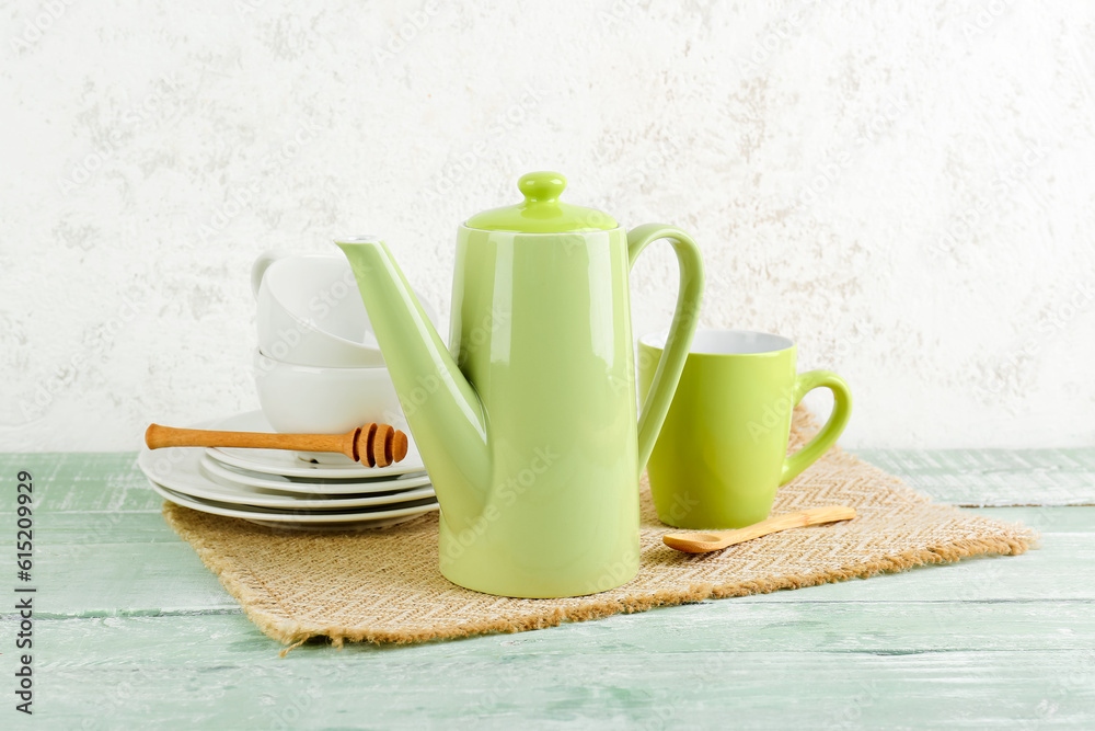 Wicker mat with stylish tea set on green wooden table