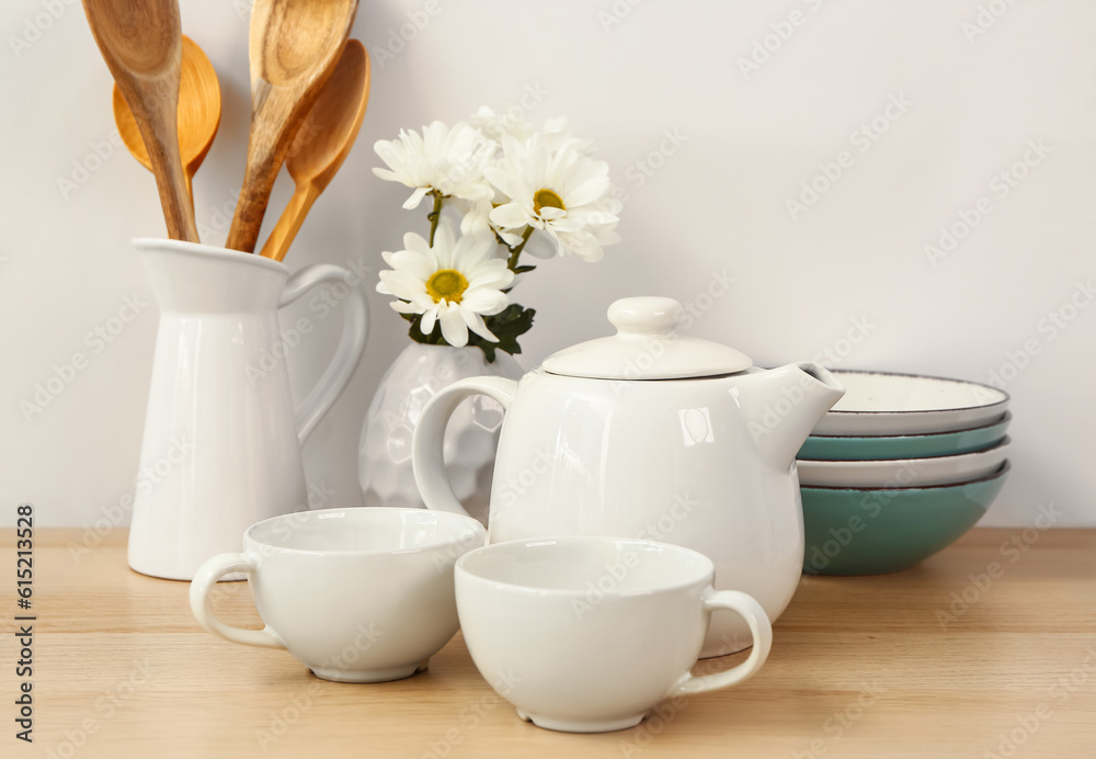 Composition with beautiful tea set, flowers and different kitchen stuff on wooden table