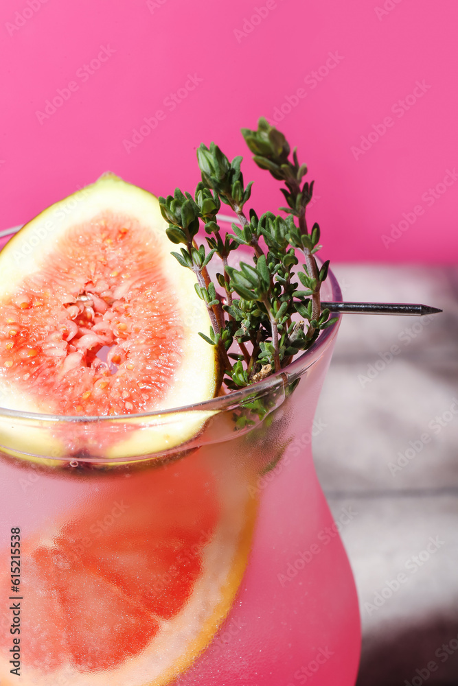 Fresh summer cocktail with fig, grapefruit and thyme near pink wall