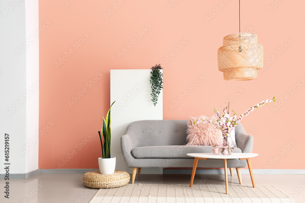 Interior of stylish living room with grey sofa and blooming sakura branches on coffee table