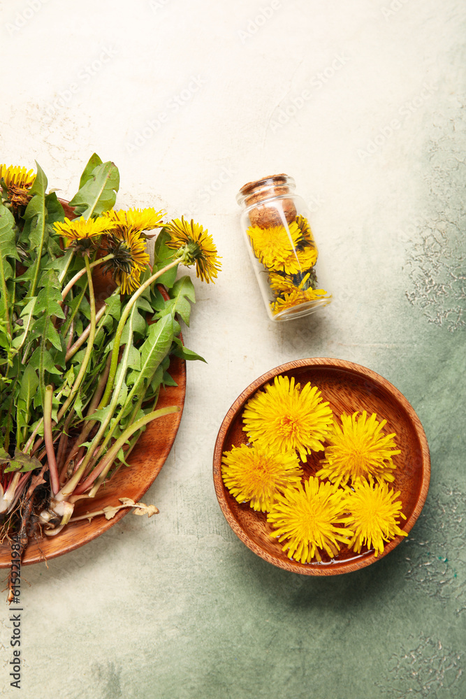 Bottle with cosmetic oil and bowl of dandelion flowers on color background