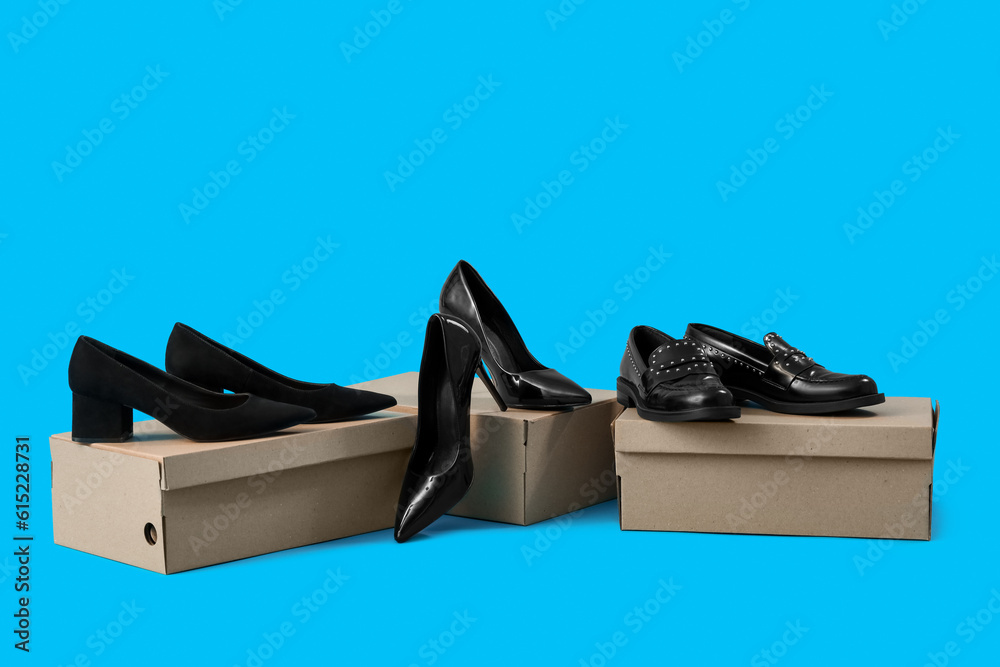 Cardboard boxes with different female black shoes on blue background