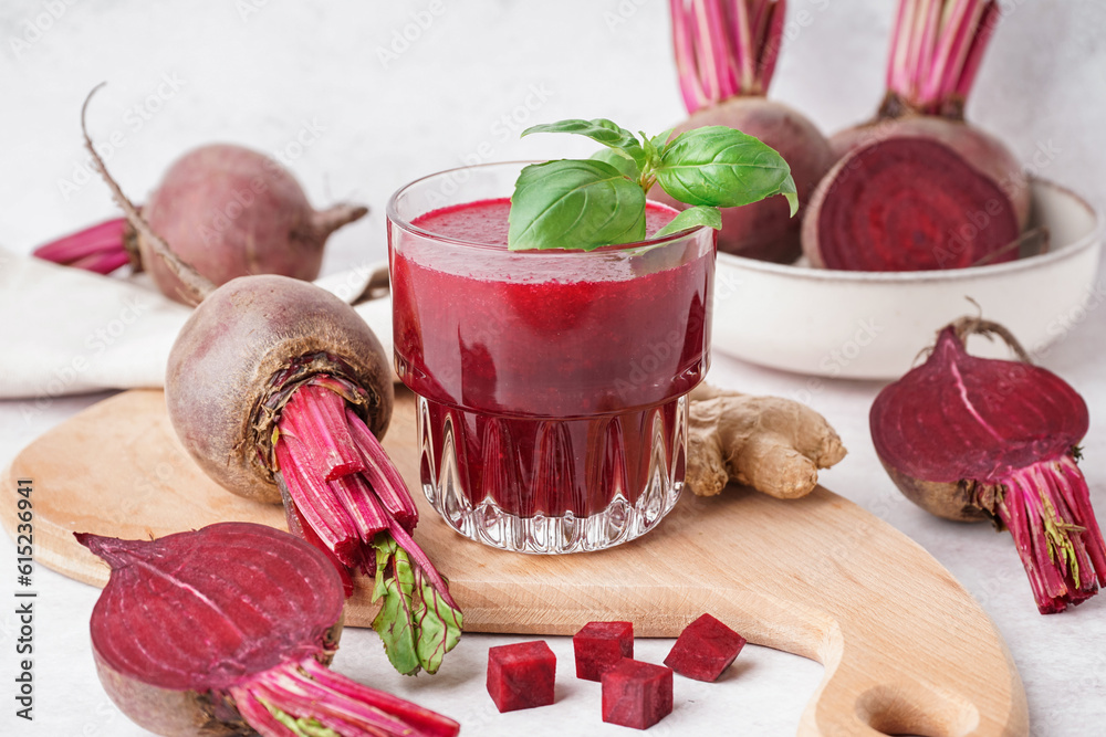 Glass of fresh beetroot juice with vegetables on light background