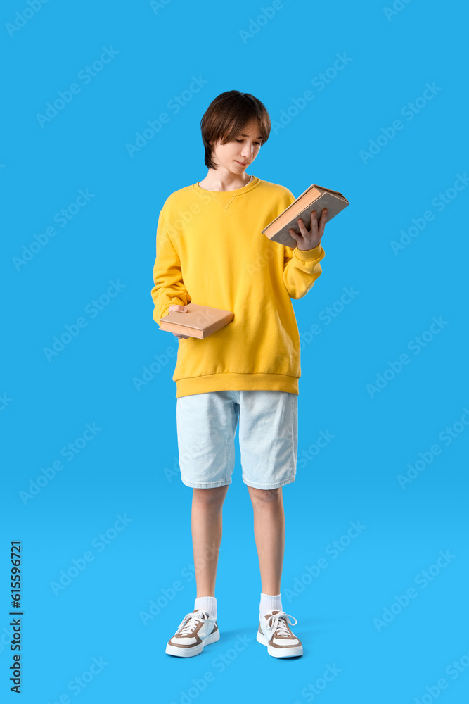 Teenage boy with books on blue background