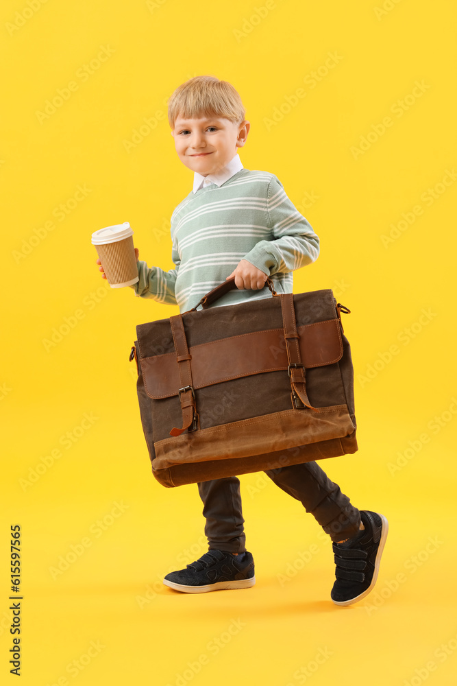 Funny little businessman with cup of coffee and briefcase on yellow background