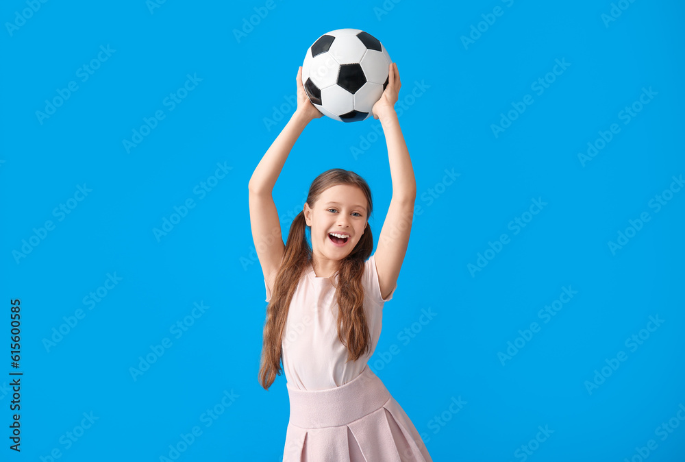 Happy little girl with soccer ball on blue background