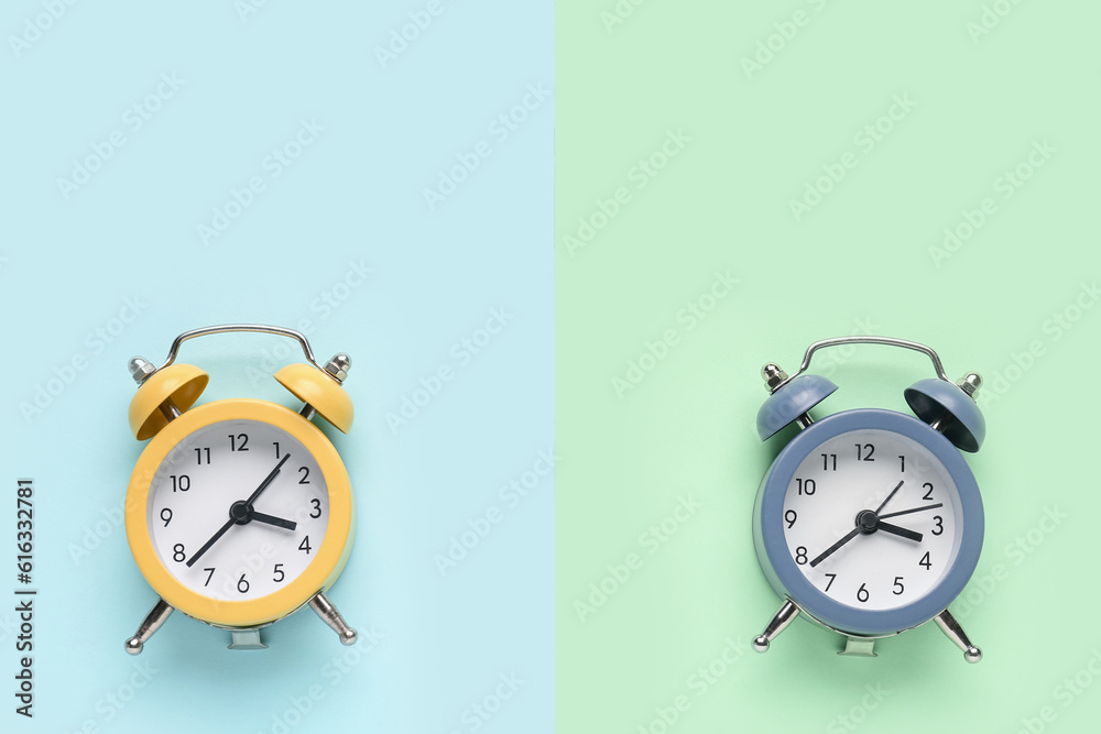 Two alarm clocks on color background