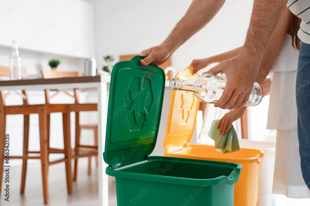 Family sorting garbage with recycle bins in kitchen, closeup