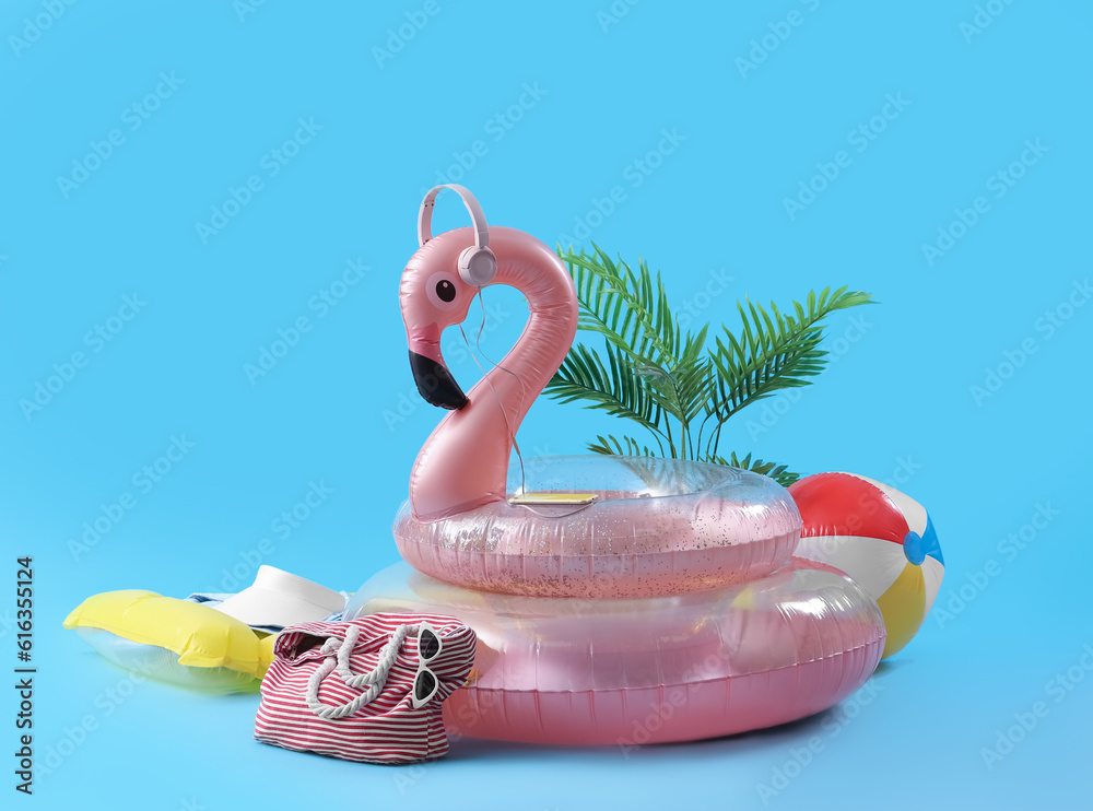 Creative composition with inflatable rings, plant and beach accessories on blue background. Summer v