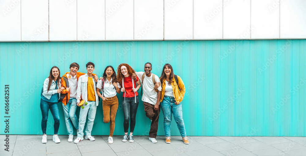 Diverse college students standing together on a blue wall - Photo portrait of multiracial teenagers 