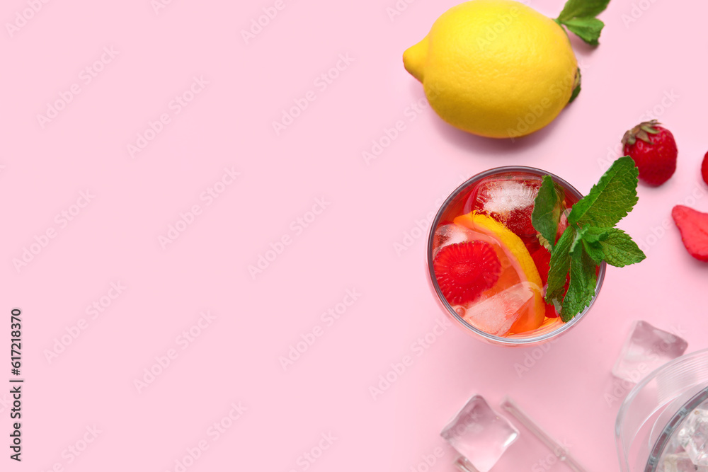 Glass of infused water with strawberry and lemon on pink background