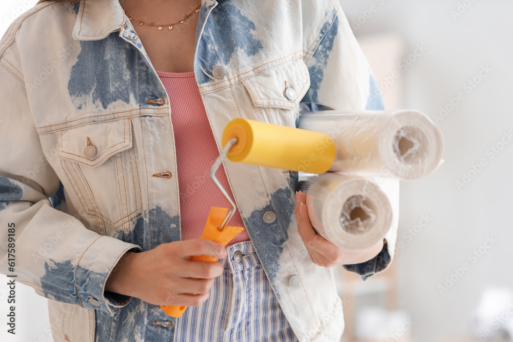 Young woman with wallpapers and roller at home, closeup
