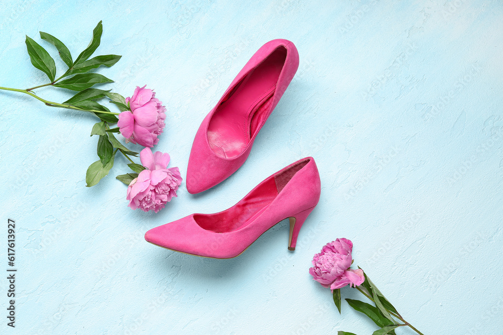 Composition with stylish high heels and beautiful peony flowers on light blue background