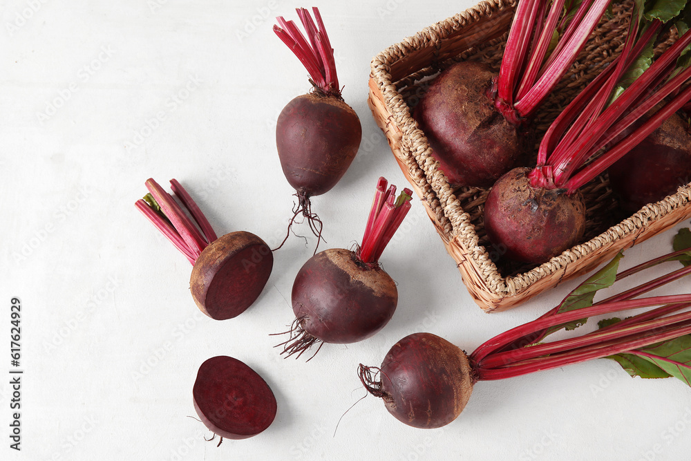 Wicker basket with fresh beets on light background