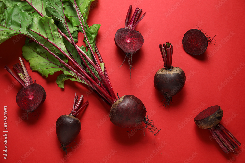 Fresh beets with green leaves on red background