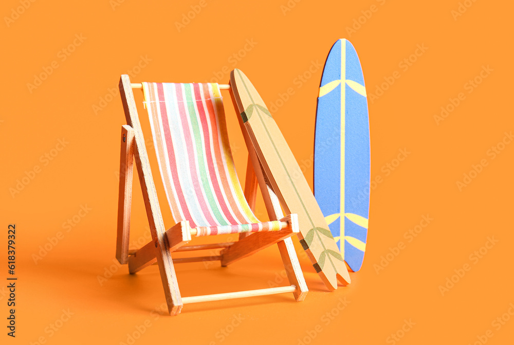 Composition with mini surfboards and deckchair on orange background