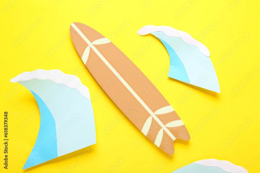 Creative composition with mini surfboard and paper waves on yellow background